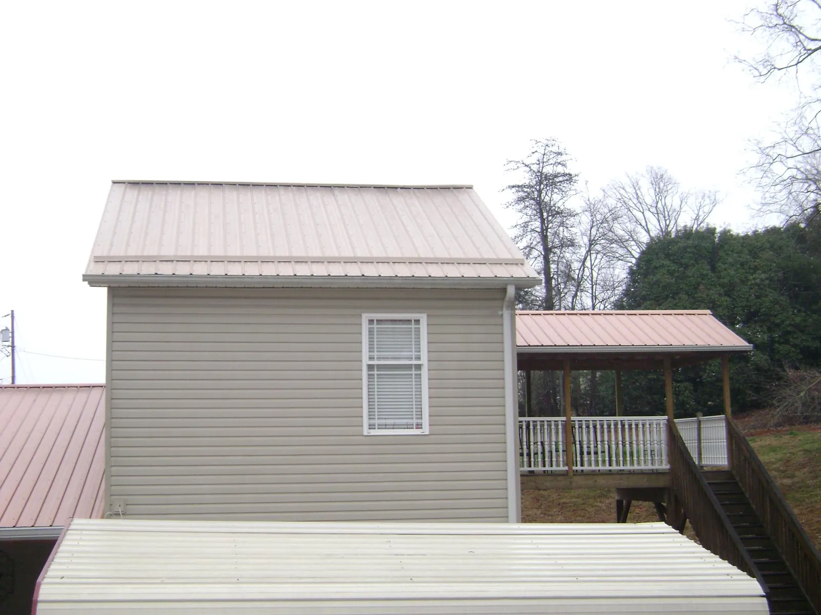 Tan metal roofs on a two story addition and attached porch, from a Roof Replacement job in Viola